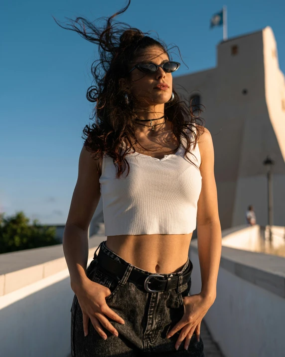 a beautiful young woman standing on top of a roof, by Robbie Trevino, wearing crop top, implanted sunglasses, profile image, low quality photo