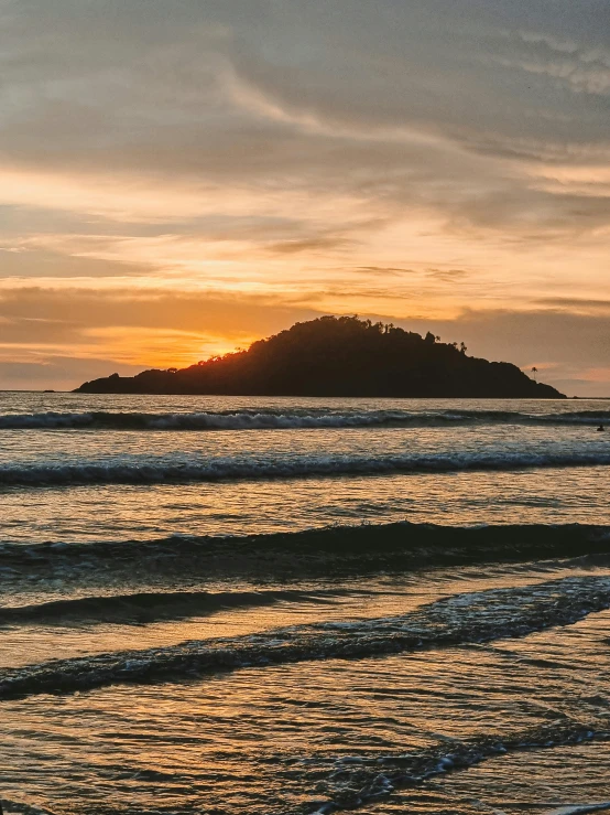 a man standing on top of a beach next to the ocean, by Matt Stewart, pexels contest winner, dappled golden sunset, islands, sri lankan landscape, thumbnail