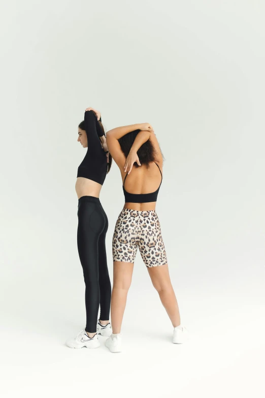 a couple of women standing next to each other, crop yoga short, animal skins, over the shoulder shot, full product shot