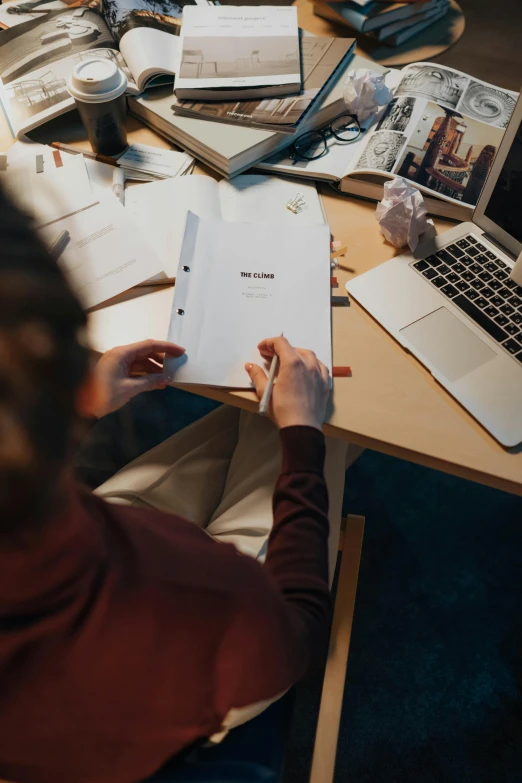 a woman sitting at a table in front of a laptop computer, by Carey Morris, pexels contest winner, lined paper, designer product, text on paper, high angle shot