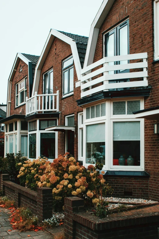a row of houses sitting on the side of a road, by Jacob Toorenvliet, unsplash, arts and crafts movement, window. netherlands tavern, sunny bay window, suburban neighborhood, red bricks