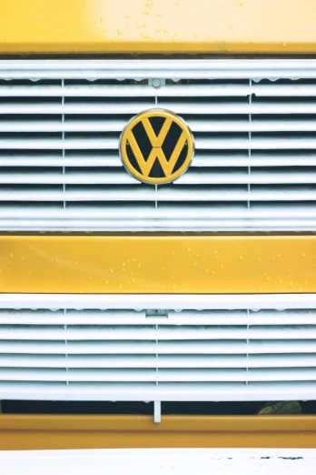 a yellow vw bus is parked in the snow, unsplash, emblem, square, grill, glossy white metal