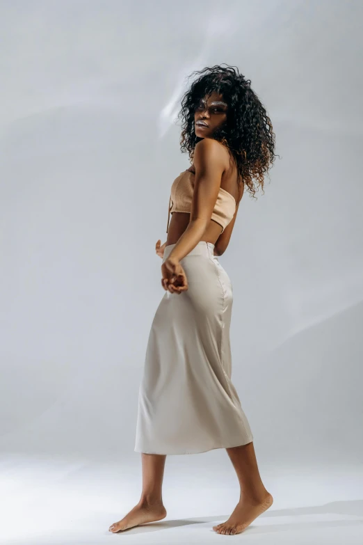 a woman standing in front of a white background, trending on pexels, renaissance, wearing a tanktop and skirt, light-brown skin, r&b, white silky outfit