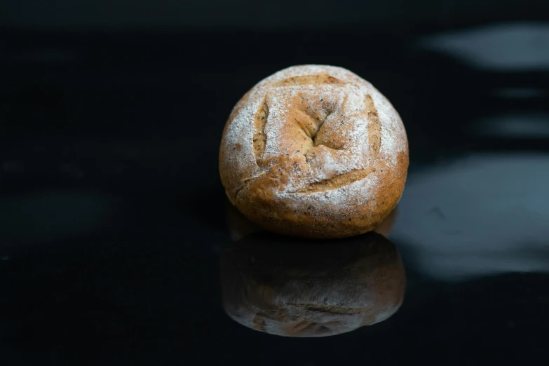 a loaf of bread sitting on top of a table, a portrait, by Mathias Kollros, unsplash, round format, on black background, miniature product photo, thumbnail