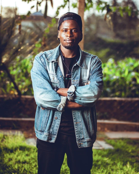 a man standing in the grass with his arms crossed, an album cover, by Stokely Webster, pexels contest winner, happening, maria borges, confident stance, standing in a dimly lit room, casual pose