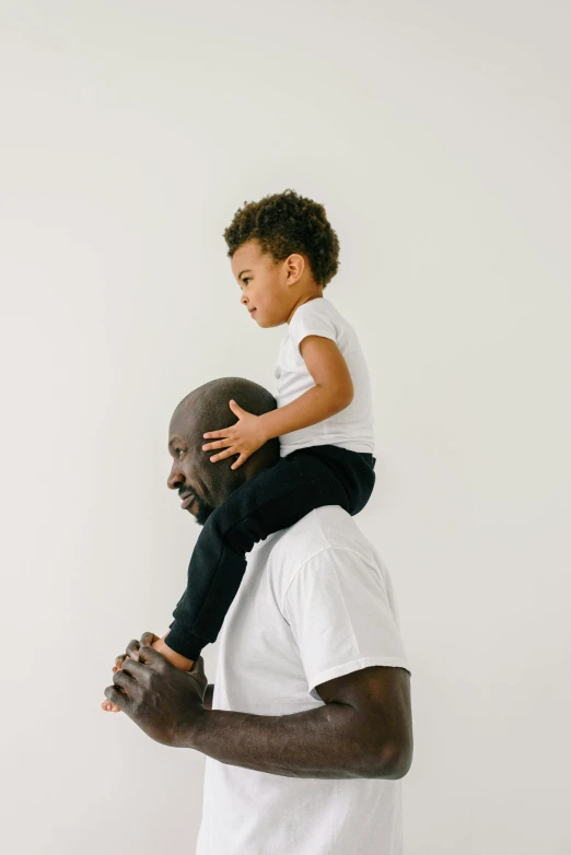 a man holding a small child on his shoulders, by Winona Nelson, unsplash, dada, portrait of kobe bryant, black on white background, saddle up, in profile