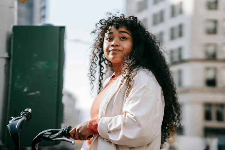 a woman standing next to a bike on a city street, trending on pexels, black curly hair, portrait of teenage girl, large)}], headshot profile picture