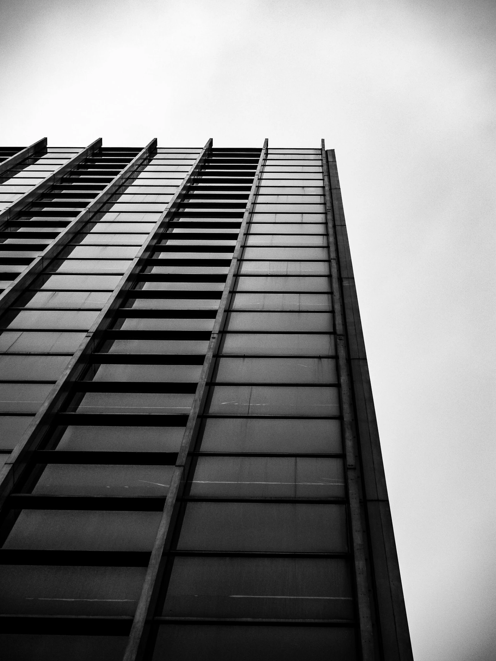 a black and white photo of a tall building, by Adam Rex, unsplash, square lines, full of glass. cgsociety, view from ground, high quality photo