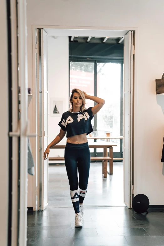 a woman that is standing in a room, by Arabella Rankin, trending on unsplash, cute sportswear, exiting store, fitness model, graphic tees