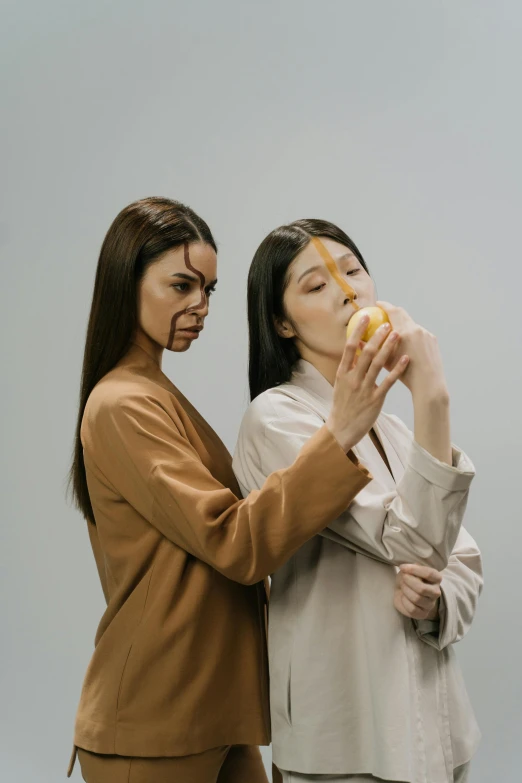 two women standing next to each other eating donuts, by Attila Meszlenyi, trending on pexels, realism, on a gray background, eating rotting fruit, asian descent, mustard and ketchup