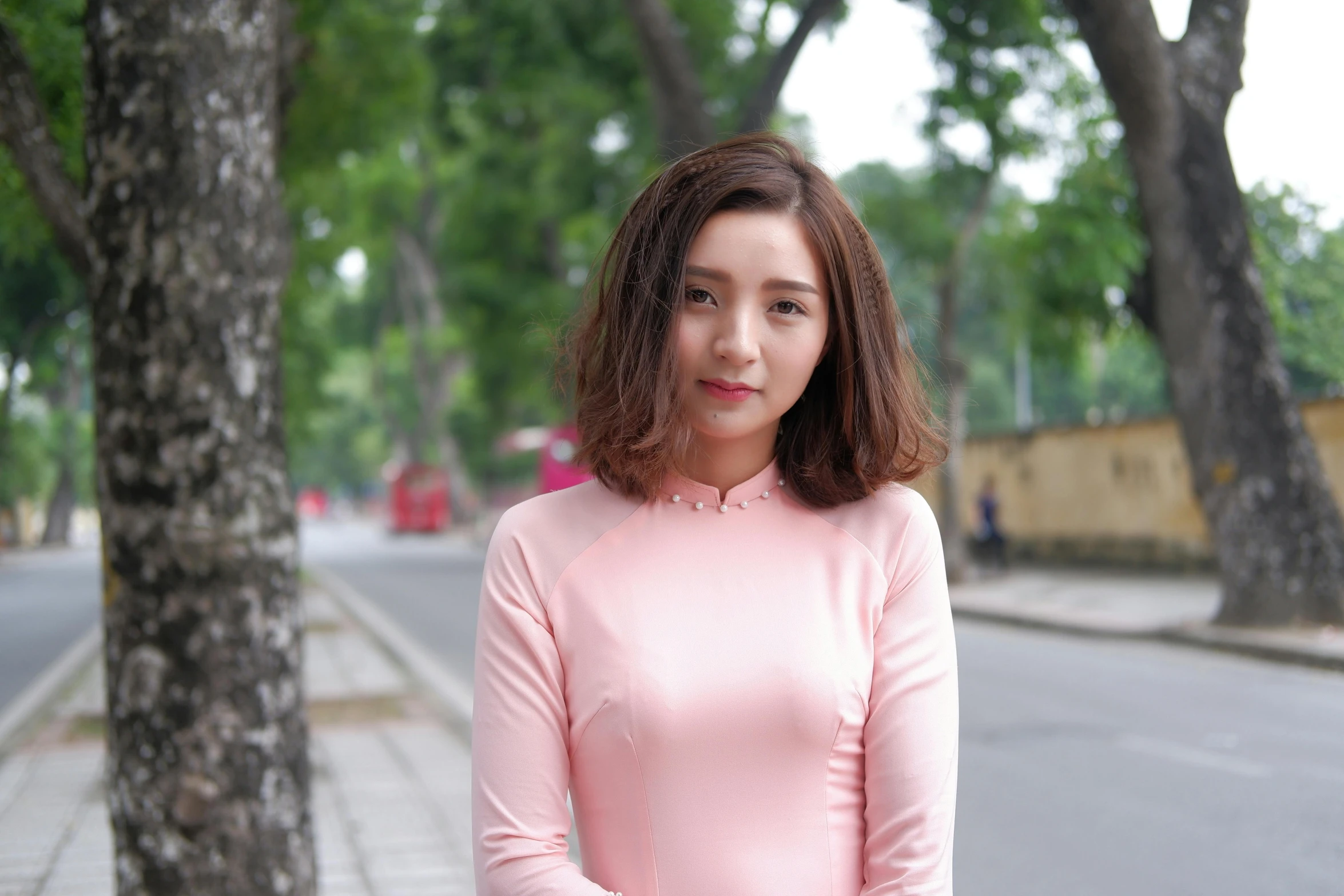 a woman in a pink dress standing next to a tree, ao dai, 15081959 21121991 01012000 4k, square, standing in street