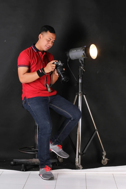 a man sitting on a chair in front of a camera, by Basuki Abdullah, general studio lighting, !!! colored photography, profile picture, lights