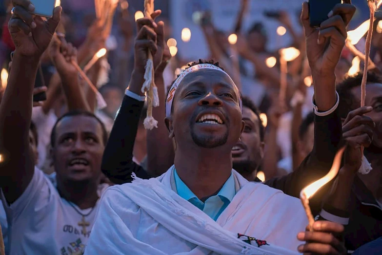 a group of people holding torches in the air, by Matija Jama, hurufiyya, holding a holy symbol, east african man with curly hair, promo image, crowds of people praying