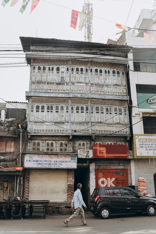 a man walking across a street next to a tall building, trending on unsplash, art nouveau, uttarakhand, dilapidated house, brown and white color scheme, shop front