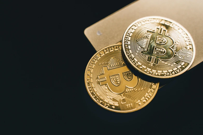 two gold bitcoins sitting next to each other, a photo, by Julia Pishtar, trending on pexels, shot on canon eos r5, black, thumbnail, one contrasting small feature