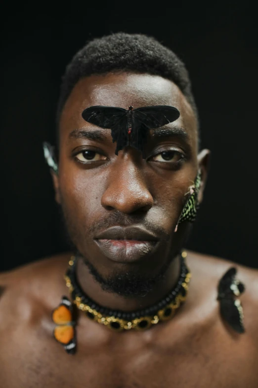 a man with a butterfly on his forehead, an album cover, trending on pexels, afrofuturism, yoruba body paint, made of insects, portrait of pele, a black choker
