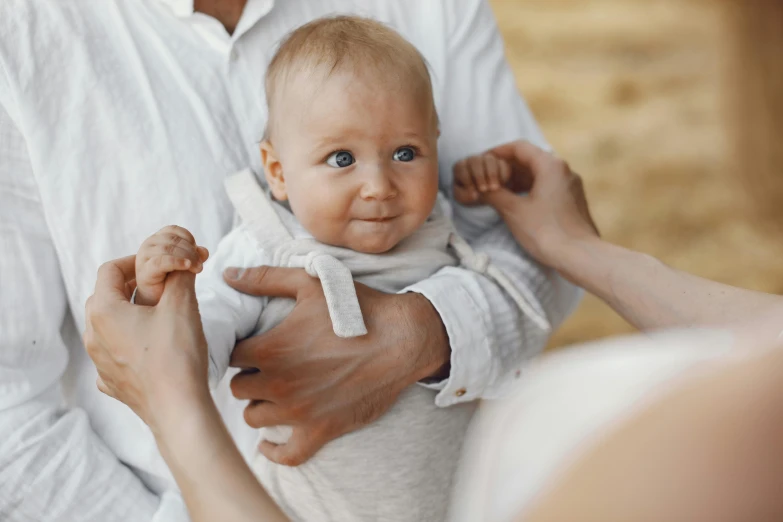 a close up of a person holding a baby, looking the camera, grey, nimble, white