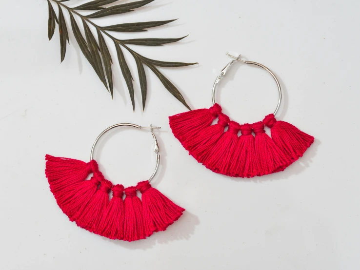 a pair of hoop earrings with red tassels, pexels, hurufiyya, featuring rhodium wires, carnation, slightly tanned, toga