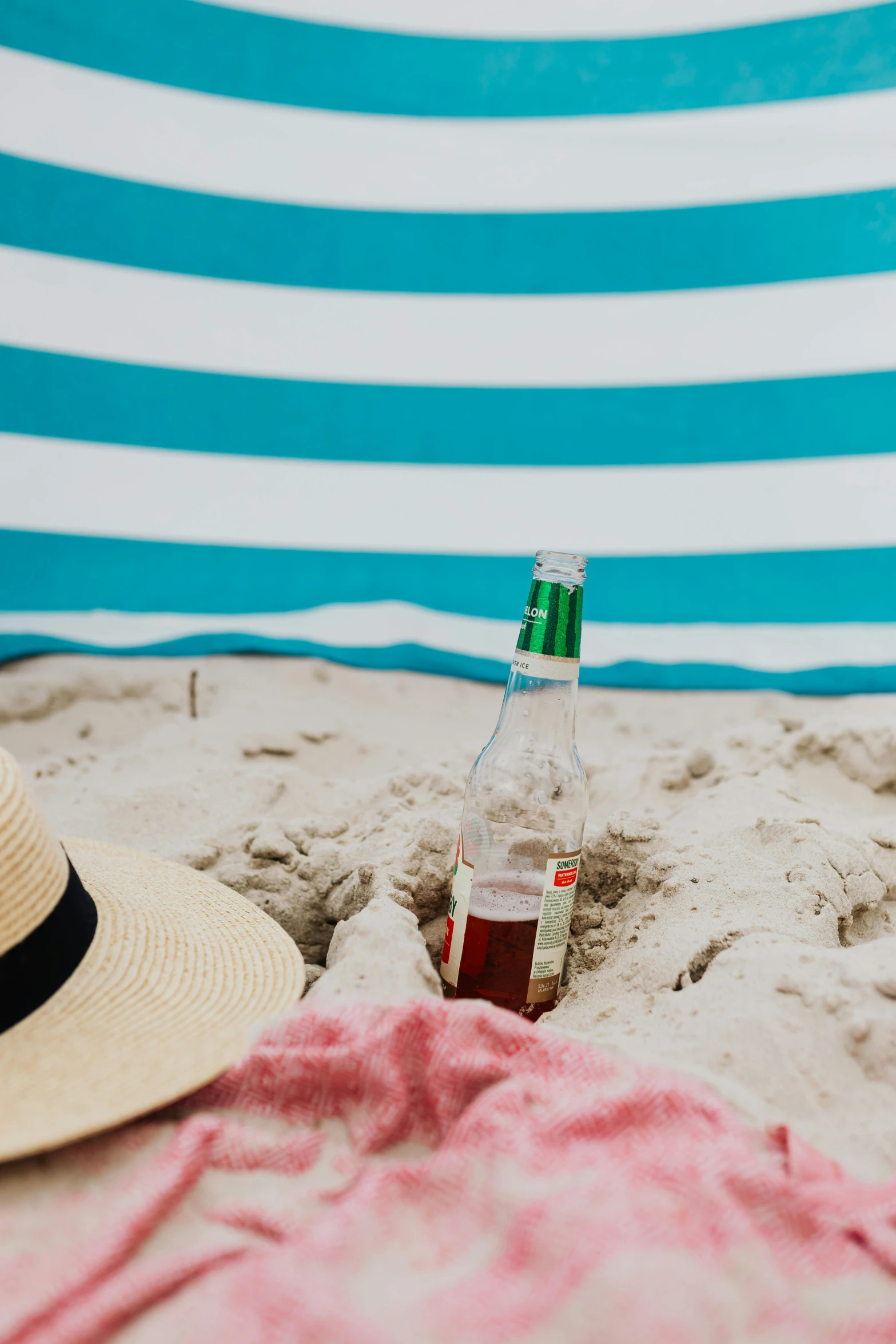 a hat sitting on top of a beach next to a bottle, striped, banner, flat lay, profile image