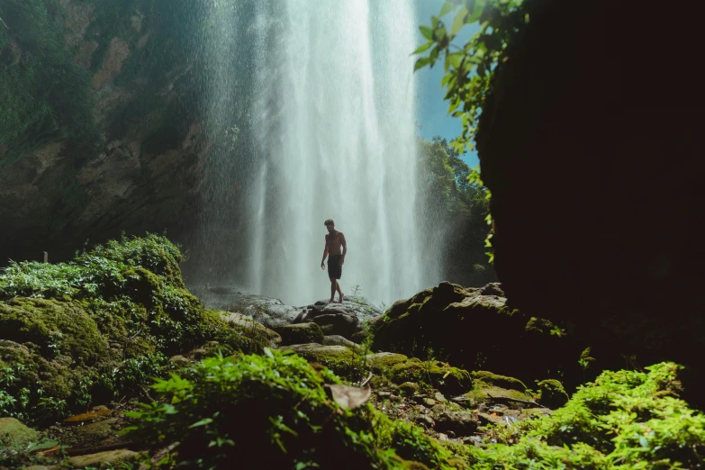 a man standing in front of a waterfall, pexels contest winner, sumatraism, avatar image, ground view shot, lush oasis, wide film still