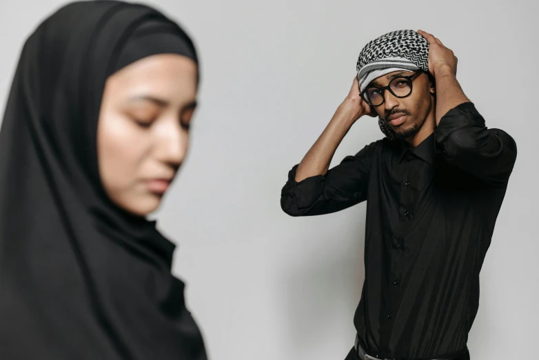a man in a black shirt and a woman in a black hijab, trending on pexels, hurufiyya, non binary model, awkward, covered head, asian man
