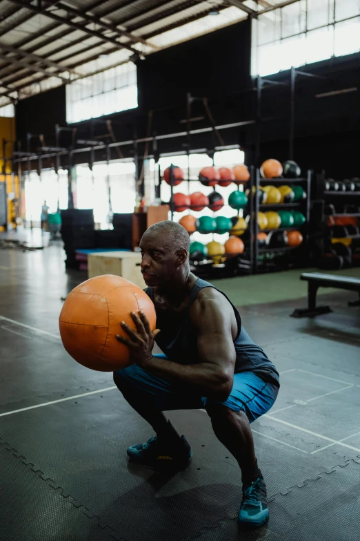 a man squatting with a basketball in a gym, pexels contest winner, man is with black skin, headspace, bald, gif