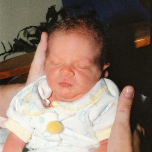 a close up of a person holding a baby, early 2 0 0 0 s, around 1 9 years old, hands pressed together in bow, photo in color