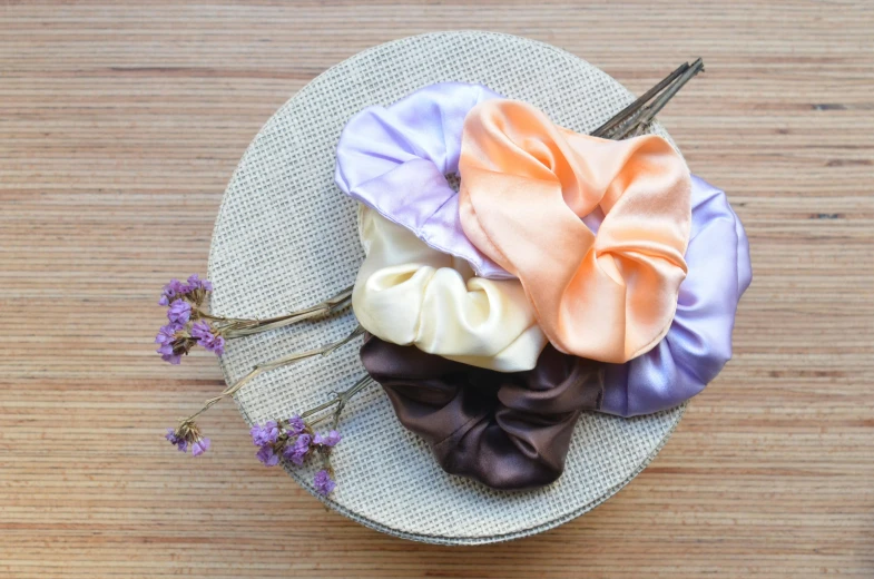 a couple of hair clips sitting on top of a wooden table, by Nina Hamnett, unsplash, renaissance, dressed in colorful silk, orange pastel colors, lilac, square