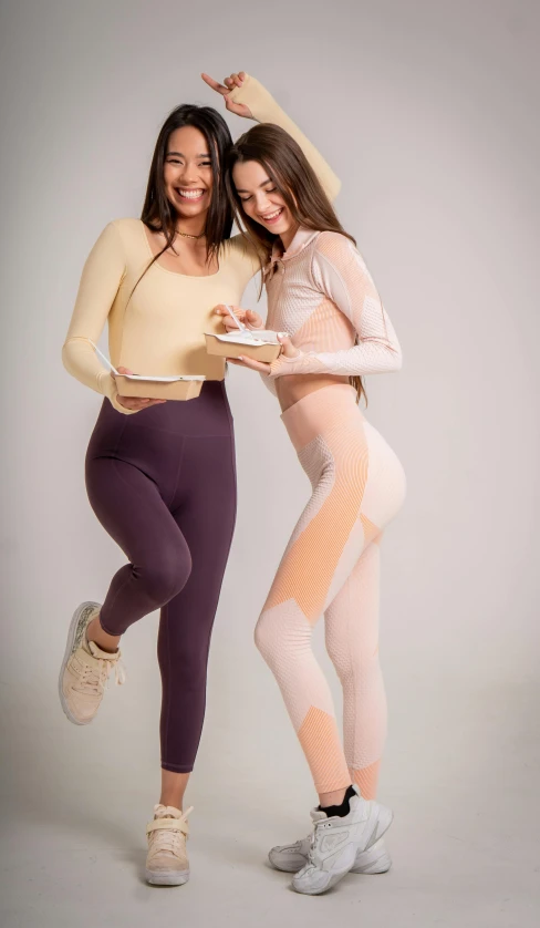 a couple of women standing next to each other, a colorized photo, trending on pexels, figuration libre, fullbodysuit, eating, product introduction photo, sport clothing