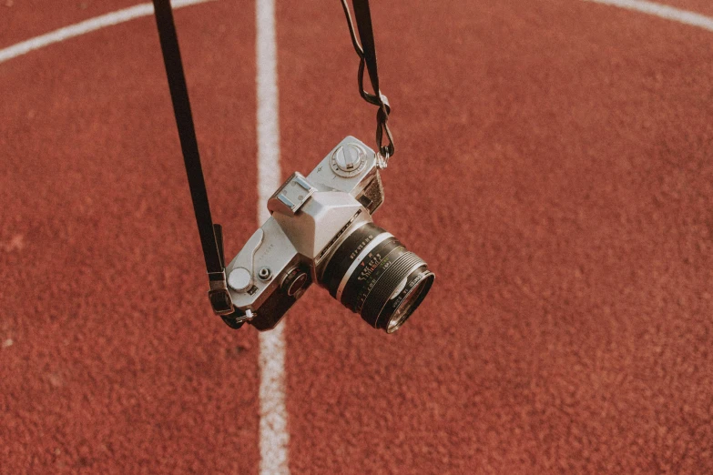 a silver camera sitting on top of a red track, pexels contest winner, sports setting, short telephoto, looking up at camera, all looking at camera