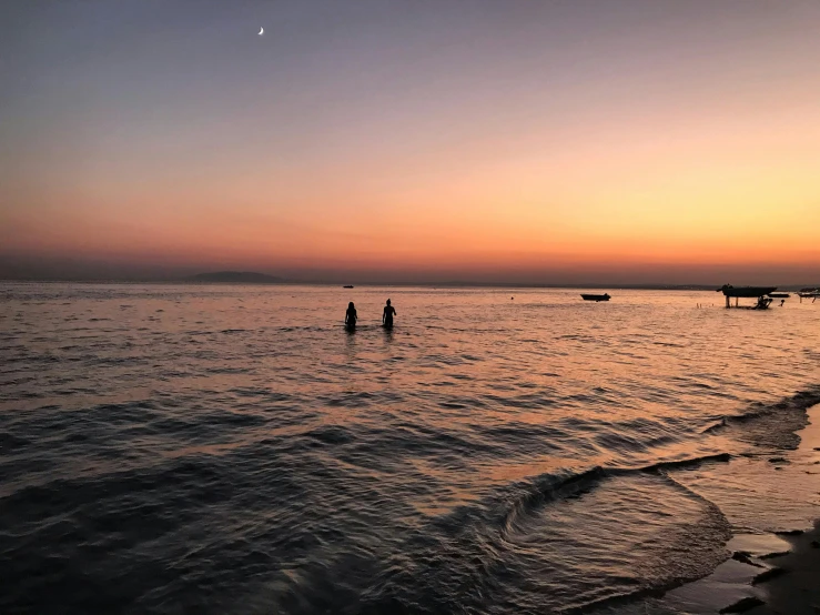 a couple of people that are standing in the water, by Maggie Hamilton, unsplash contest winner, relaxing on the beach at sunset, split near the left, seaview, photo taken with an iphone