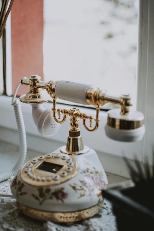 a white telephone sitting on top of a window sill, trending on pexels, art nouveau, gold plated, headset, flowery, shiny golden