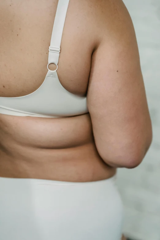 a close up of a person wearing a white bra, long-arms, bloated, background image, colour photograph