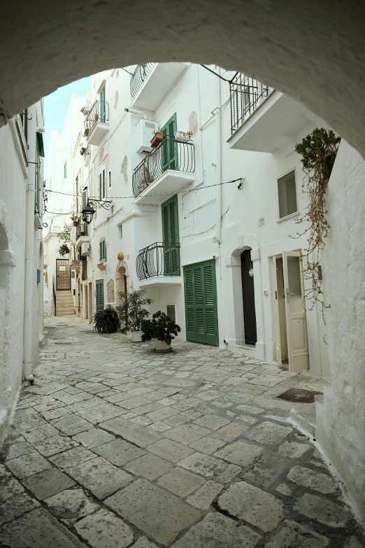an archway in the middle of a cobblestone street, by Carlo Carrà, white houses, van, panoramic view, square