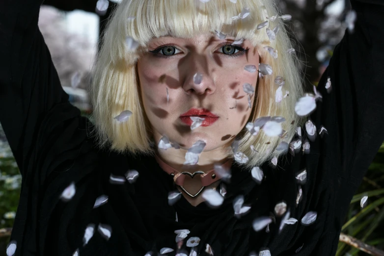 a woman with blonde hair and white feathers on her face, an album cover, inspired by Cindy Sherman, unsplash, falling petals, snowing, non-binary, taken in the early 2020s