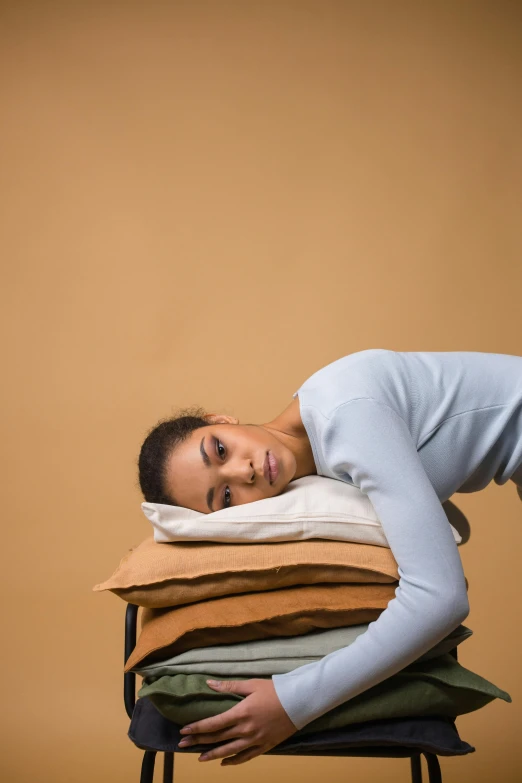 a woman laying on top of a stack of pillows, inspired by Sarah Lucas, looking sad, ashteroth, relaxed posture, brown