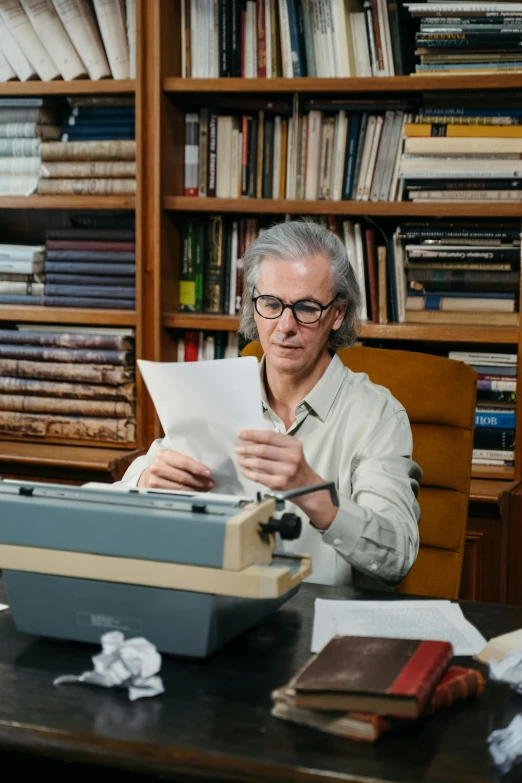 a man sitting at a desk with a typewriter, dark grey haired man, peter hurley, papers and tomes, david spade