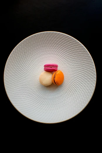 a white plate topped with macarons on top of a black table, inspired by Charles Le Roux, 4 0 0 mm, vivid), 3 - piece, circle