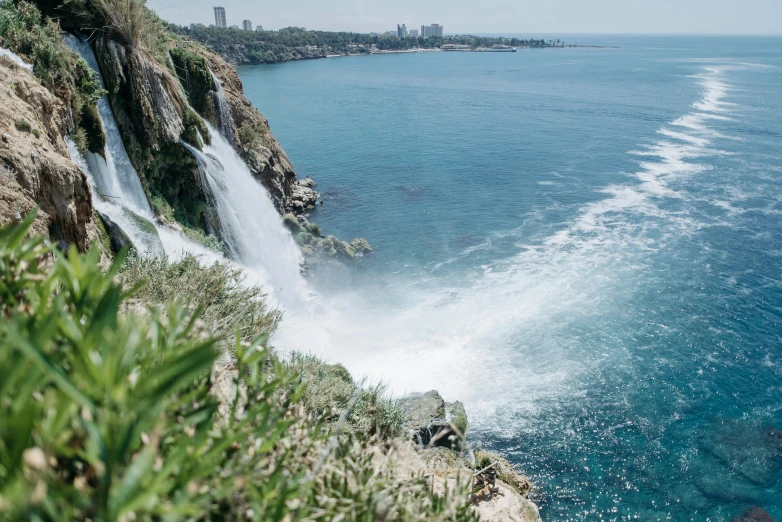 a waterfall in the middle of a large body of water, pexels contest winner, hurufiyya, next to the sea, surrounding the city, high quality product image”