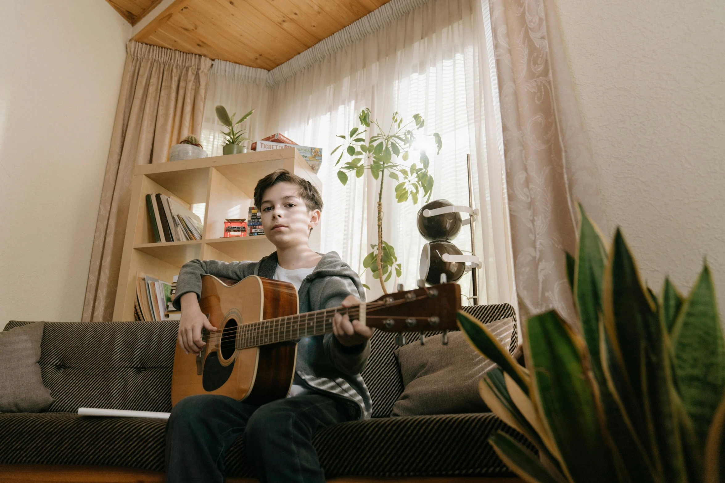 a boy sitting on a couch playing a guitar, pexels contest winner, avatar image