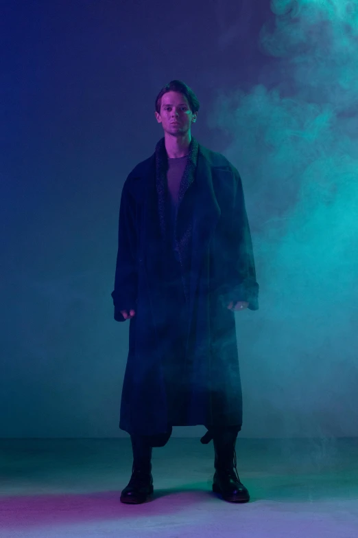 a man standing in front of a blue and green background, an album cover, unsplash, bauhaus, dark purple robes, supermodel in silent hill, full body model, ( ( theatrical ) )