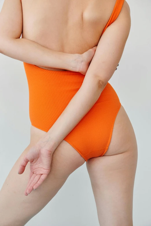 a woman in an orange bodysuit posing for a picture, by Jessie Algie, bottom view, detailed product image, vanilla, detail shot