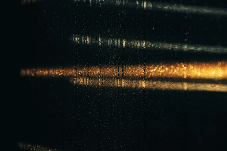 a close up of a window with rain on it, an album cover, inspired by Elsa Bleda, light and space, black and gold colors, lines of lights, texturized, in thick layers of rhythms