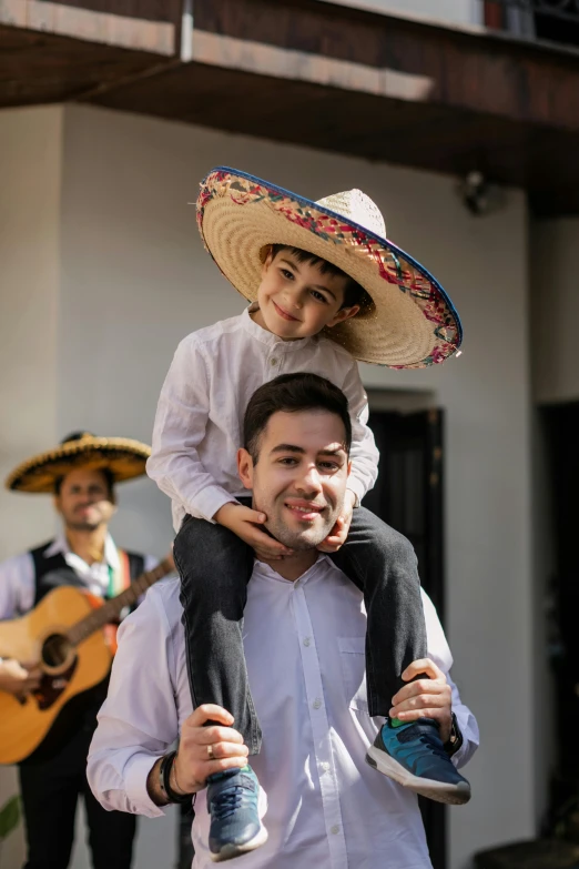 a man carrying a little boy on his shoulders, an album cover, pexels contest winner, sombrero, both smiling for the camera, david marquez, ( ( theatrical ) )