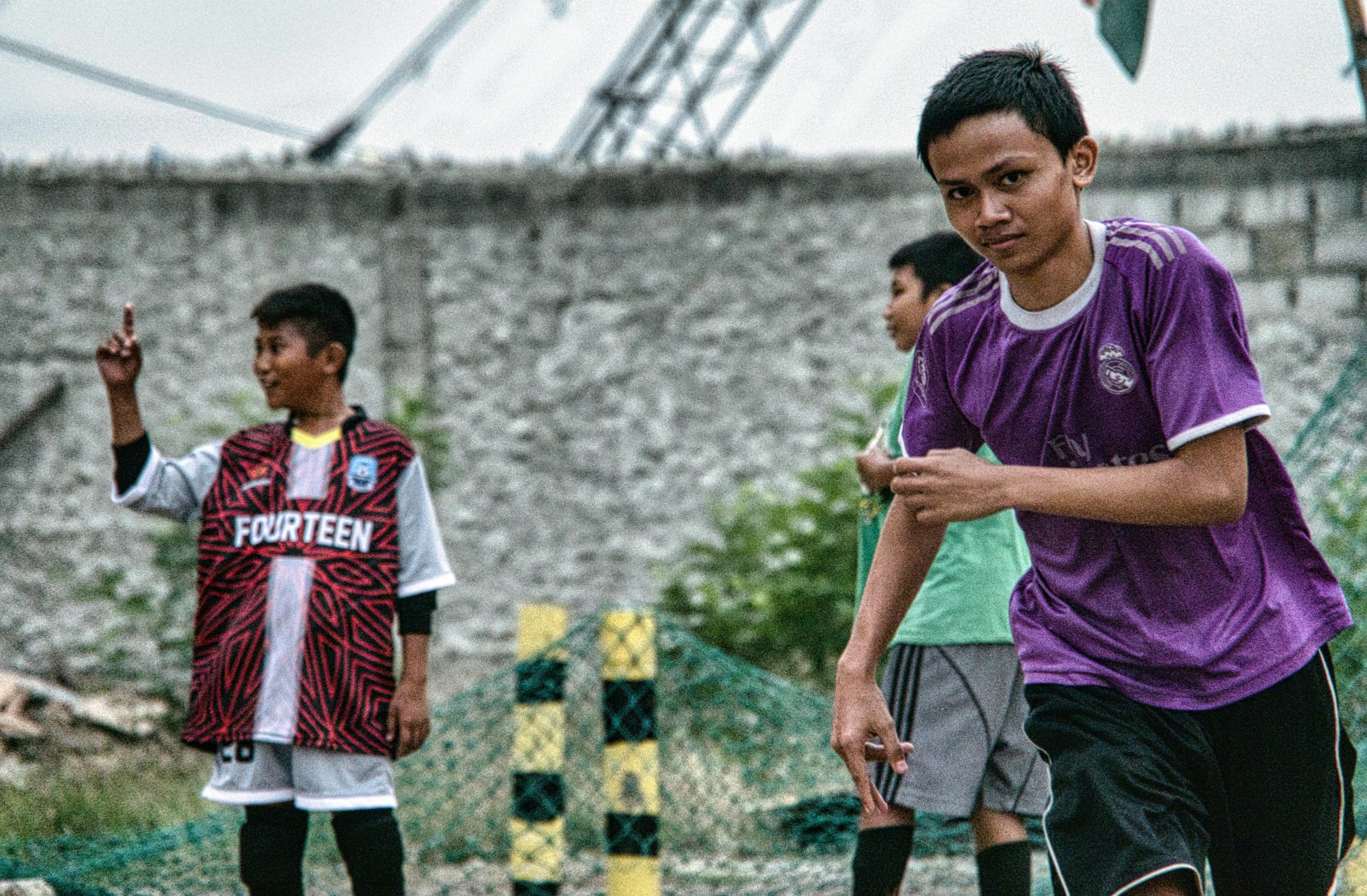 a group of young men playing a game of soccer, inspired by Erik Pevernagie, pexels contest winner, realism, indonesia, young man in a purple hoodie, aged 13, half image