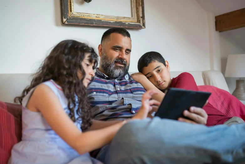 a man and two children sitting on a couch looking at a tablet, pexels, avatar image, close up photograph, enes dirig, professional shot