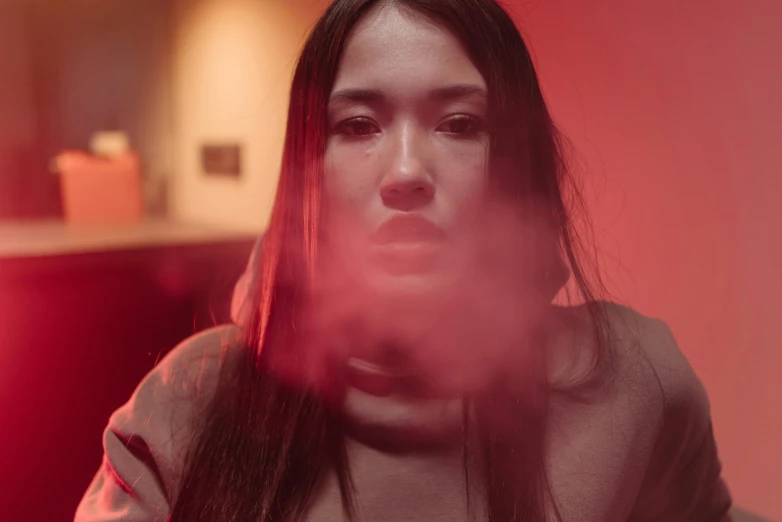 a woman sitting in front of a red light, pexels contest winner, conceptual art, with red haze, lee madgwick & liam wong, close-up portrait film still, smoke filled room