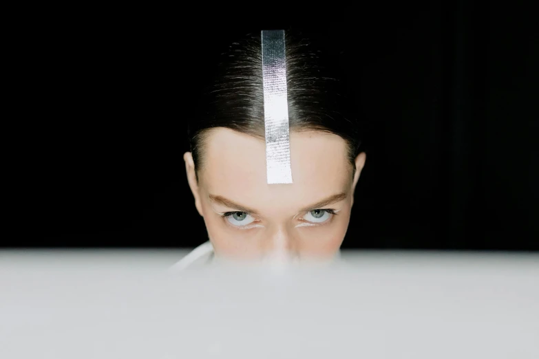 a close up of a person looking at a laptop, a hologram, inspired by Marina Abramović, unsplash, bauhaus, futuristic hairstyle, looking straight into camera, kirsi salonen, forehead jewelry