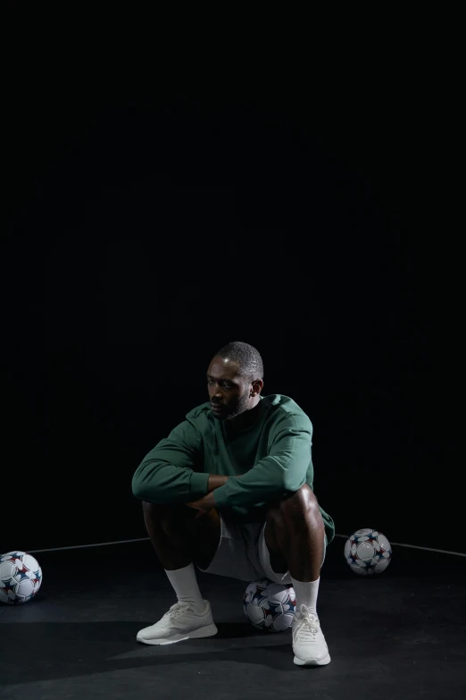 a man squatting in front of soccer balls, an album cover, inspired by Paul Georges, pexels contest winner, realism, jaylen brown, out in the dark, laces, gray men