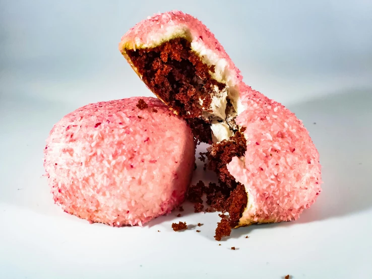 a pink donut with a bite taken out of it, by Julia Pishtar, rocky roads, red velvet, licorice allsort filling, polaeized light